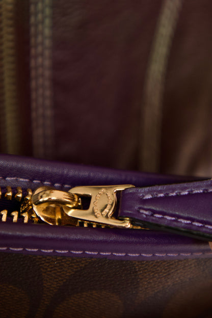 Détail fermeture éclair dorée avec finition cuir mauve sur sac Coach