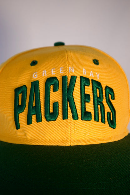 Détail logo Packers brodé en vert sur casquette jaune, style vintage NFL